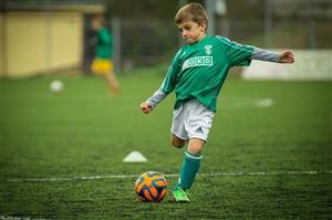 A Young Boy Kicking A Soccer Ball During Game